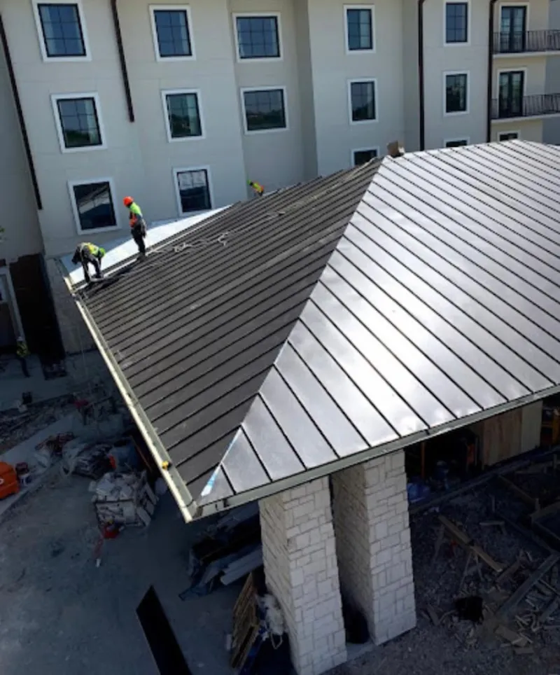 Crew installing standing seam metal roof panels on a commercial project in Media